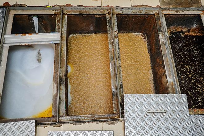 food service facility maintenance personnel cleaning a grease trap